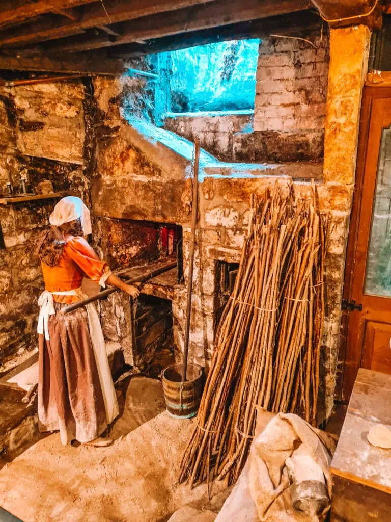 Mannequin woman in old fashioned clothes stands in front of oven