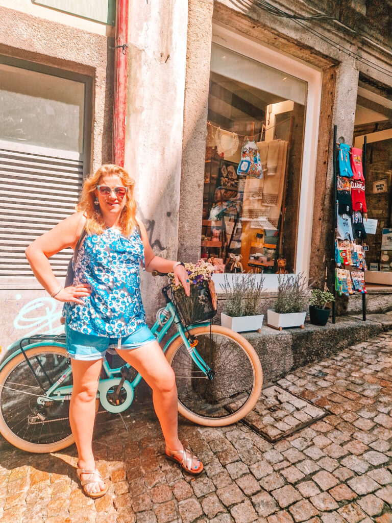 Em standing by a bike outside a shop in Porto