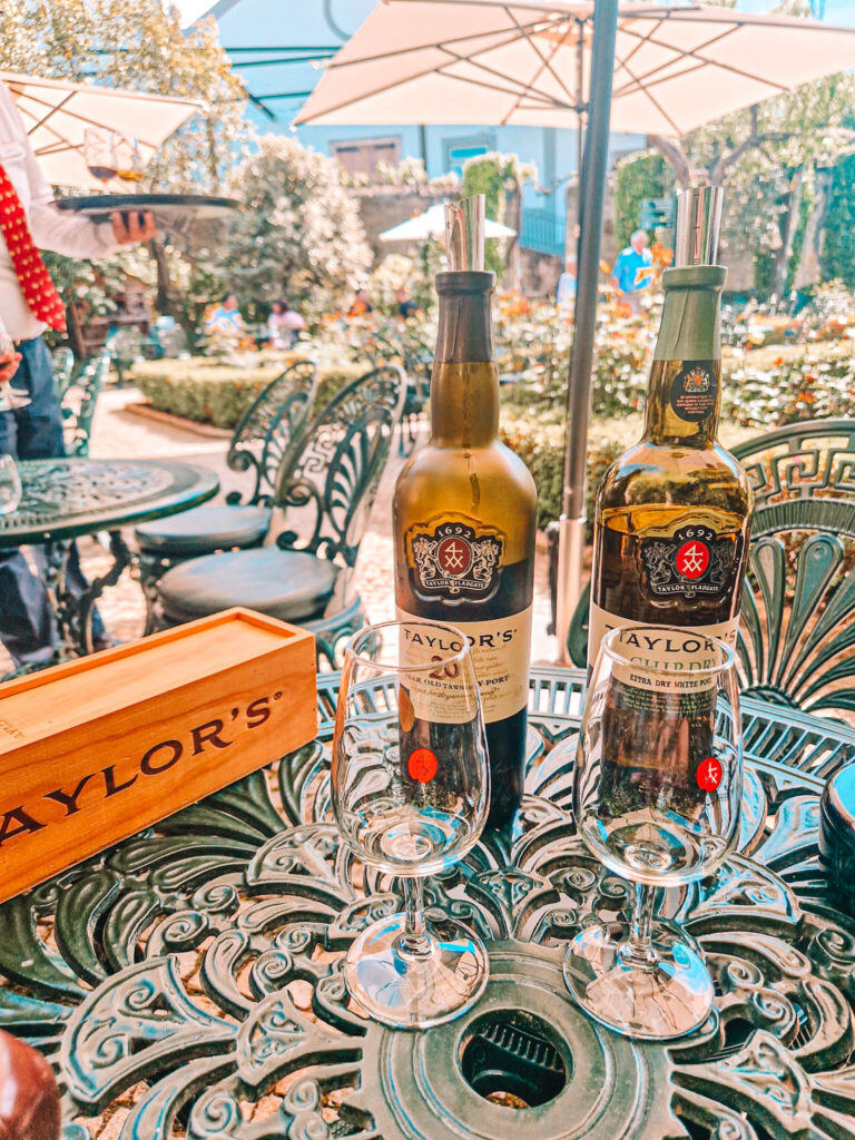 Two bottles of port and glasss on a table in the gardens at Taylors