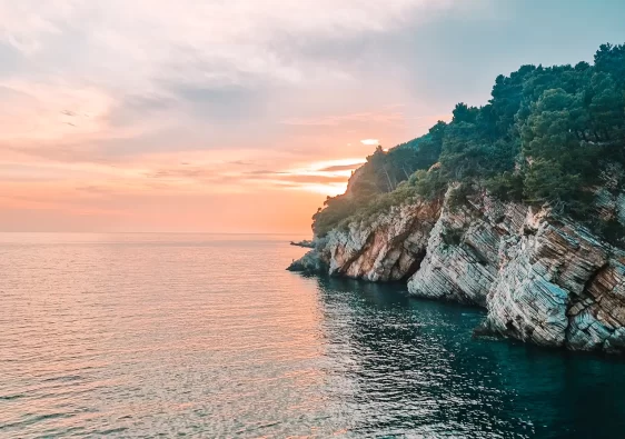 Sun setting behind a cliff seen from water