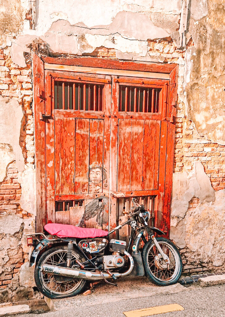 Street art of a boy, with a real motorbike in front