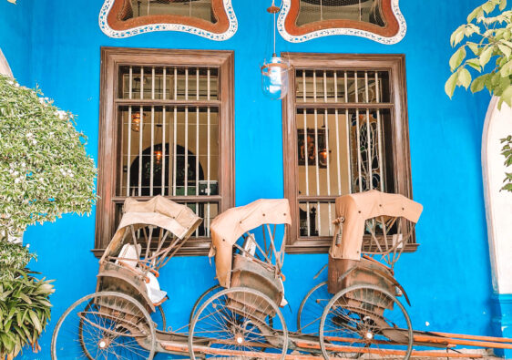 Three rickshaws against a blue wall