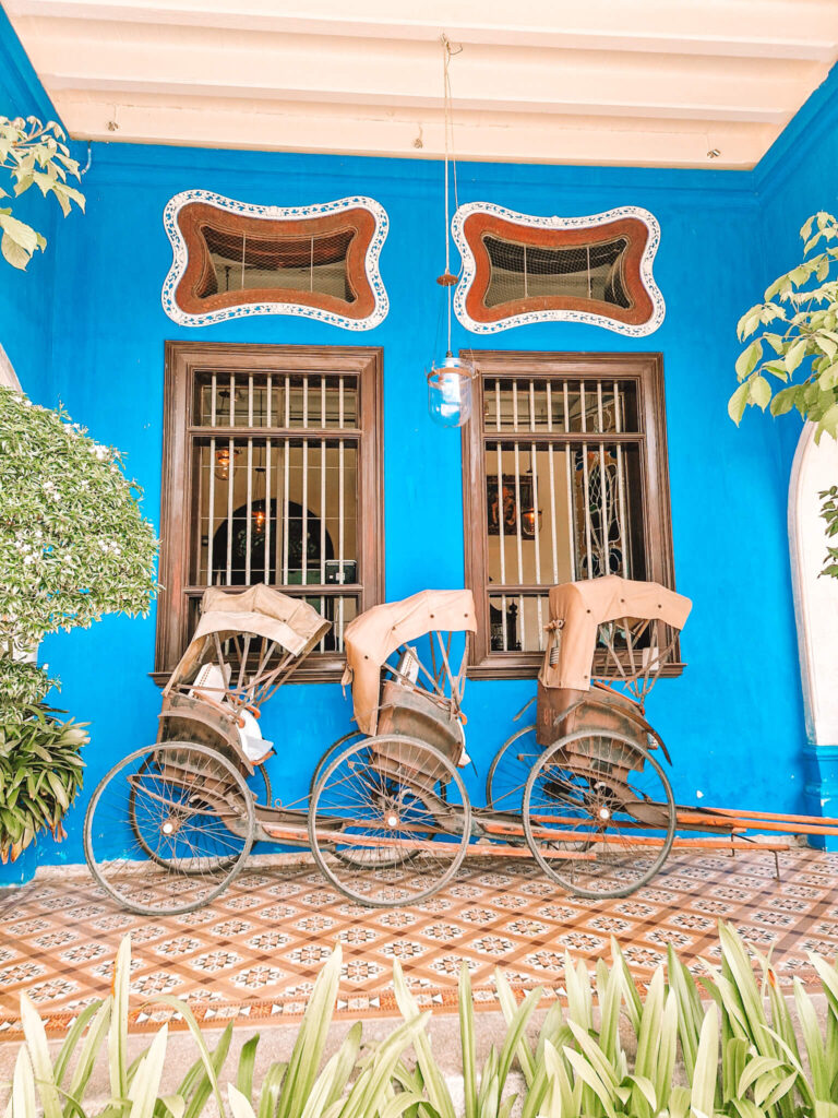 Three rickshaws against a blue wall