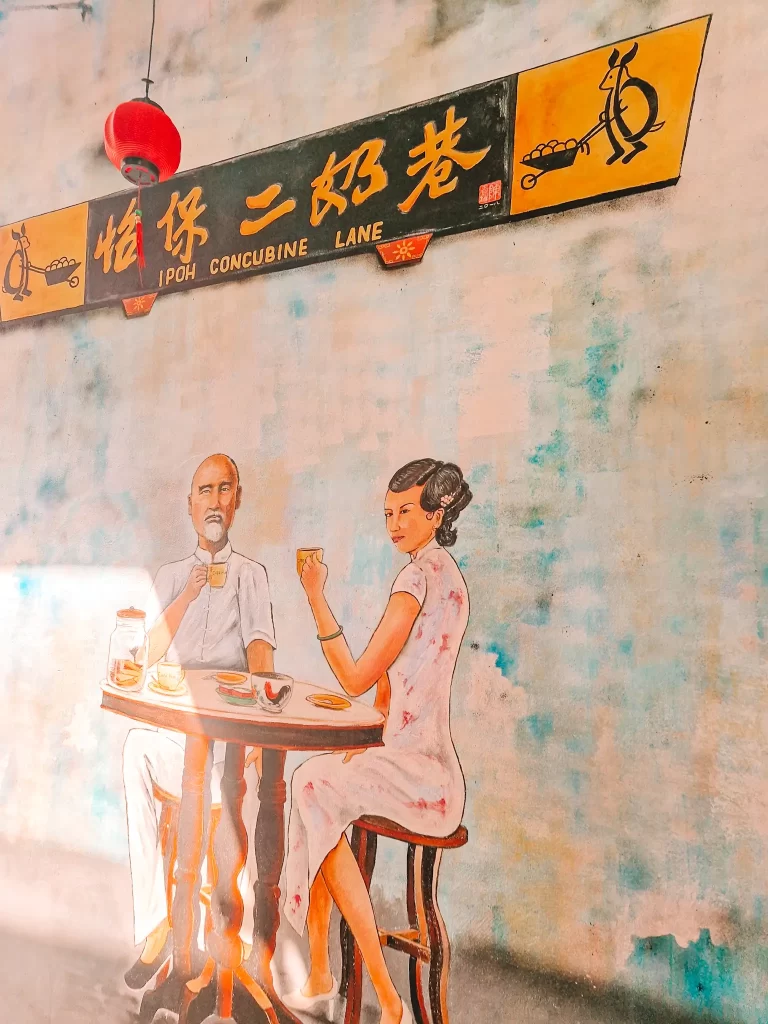 Street art mural of a man and a woman at a table, with Chinese symbols above