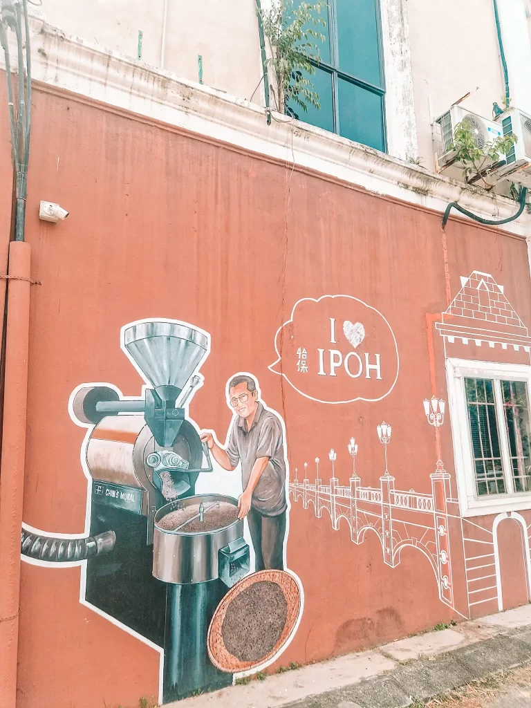 Street art of man using a coffee machine with the words "I heart Ipoh" in a speech bubble next to him