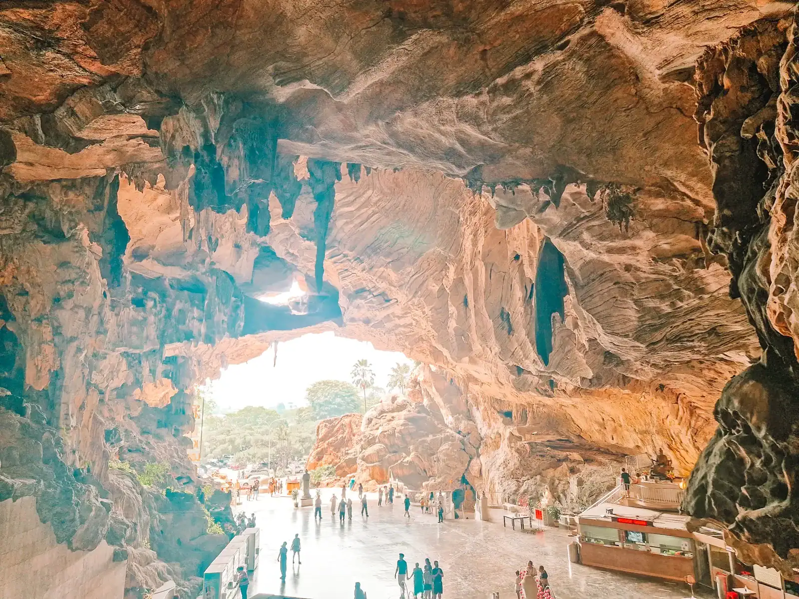 Wide-angle view of the Perak Cave Temple’s cavernous entrance with visitors silhouetted against the bright light streaming in—capturing the scale and wonder of this must-see Ipoh spot.