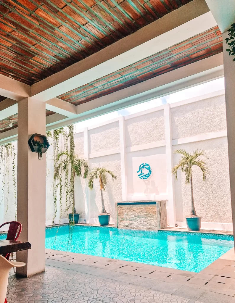 Small swimming pool in a shaded courtyard with potted palm trees