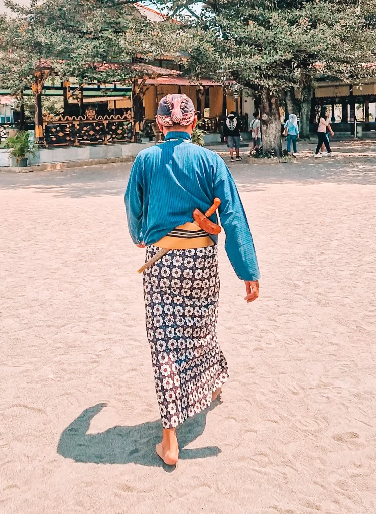 Man walking away in traditional Javanese clothes with a dagger tucked into his belt