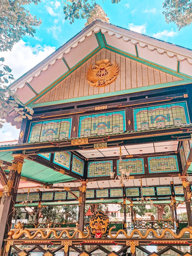 Elaborate multi coloured wooden building with pointed roof and decorative screens