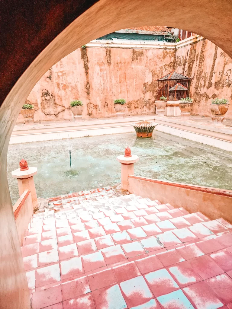 Stairs leading down to a water pool, under an archway