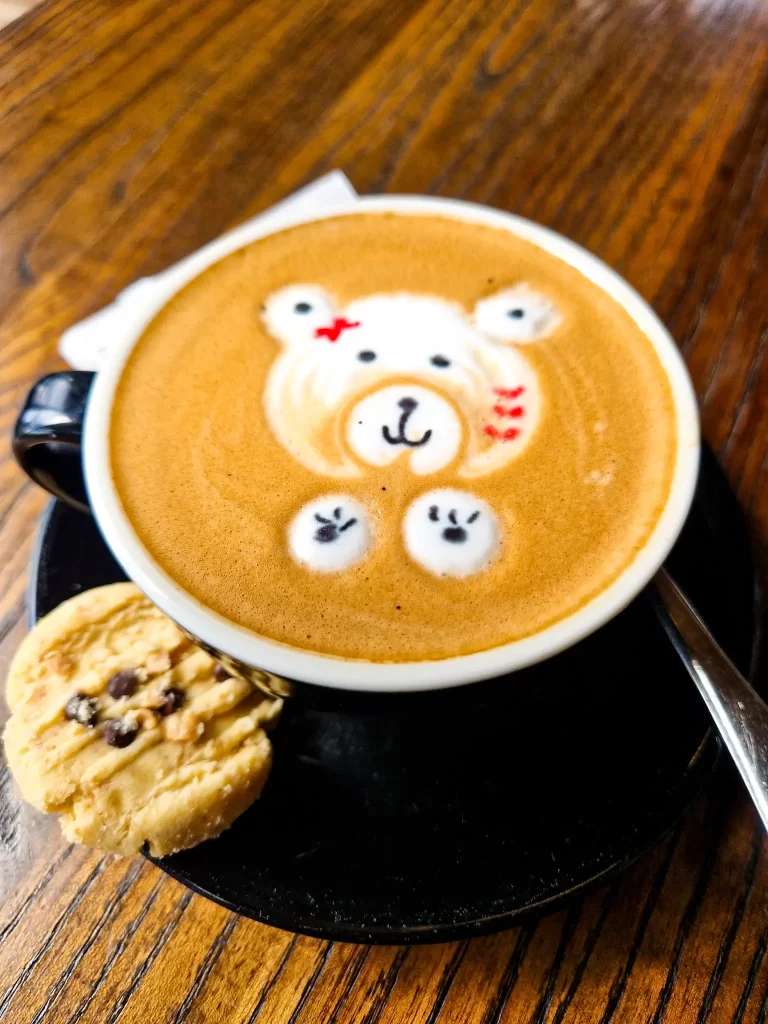 Coffee with latte art of bear and a cookie on the side