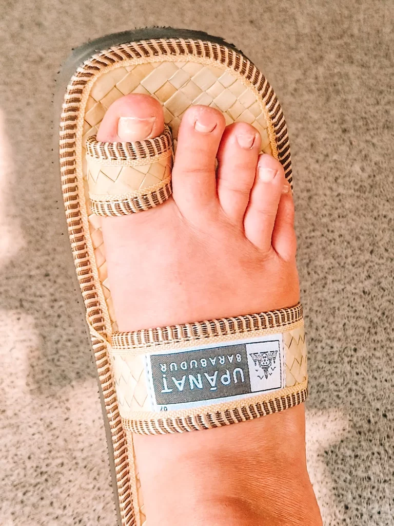 Foot in wicker sandals with logo of Borobudur on them