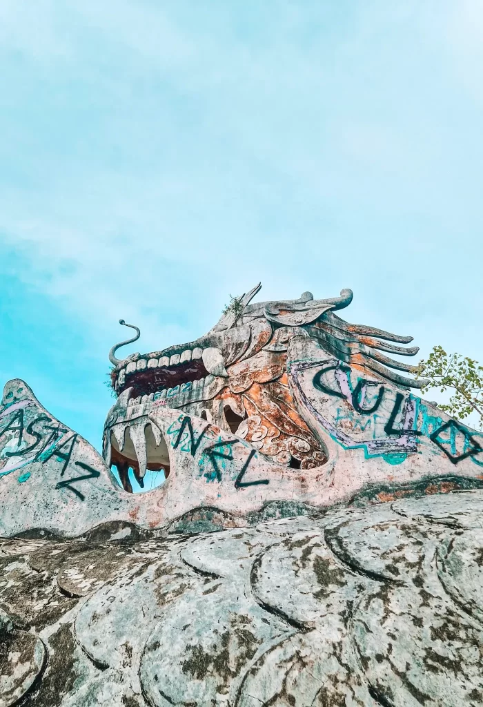 Close-up view of the graffiti-covered dragon head at the abandoned water park in Hue, Vietnam, showcasing its intricate sculptural detail—an eerie yet fascinating highlight for 2 days in Hue.