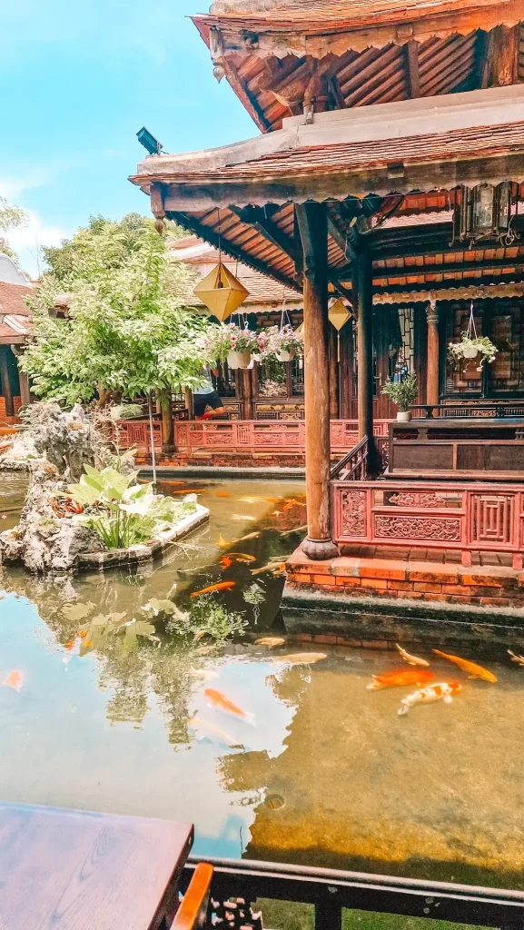 Peaceful koi pond surrounded by traditional wooden architecture and hanging lanterns, capturing the serene moments one can enjoy during 2 days in Hue.