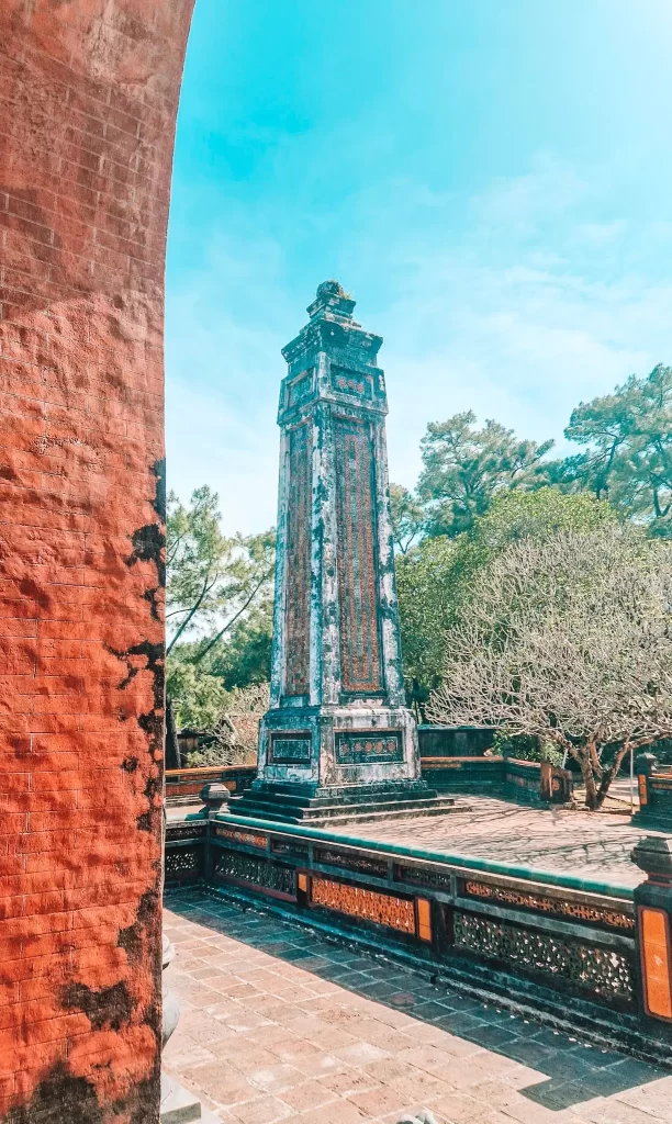Weathered stone stele surrounded by ancient walls and trees at a historic tomb complex, offering a glimpse into imperial history during 2 days in Hue.