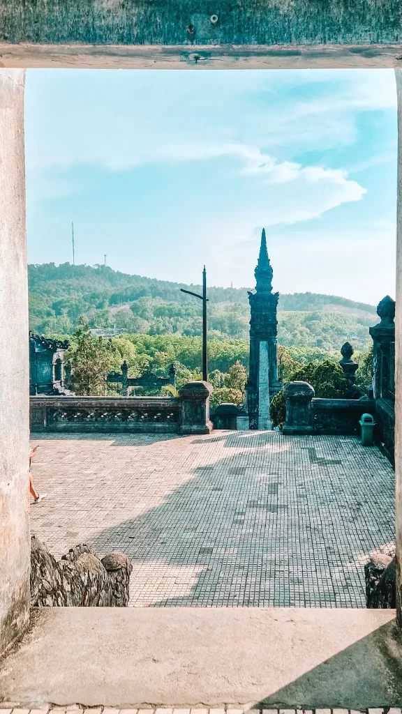  Scenic view framed by an ancient stone gateway, looking out onto tiled courtyards, lush hills, and historic spires, showcasing the timeless landscapes explored during 2 days in Hue.
