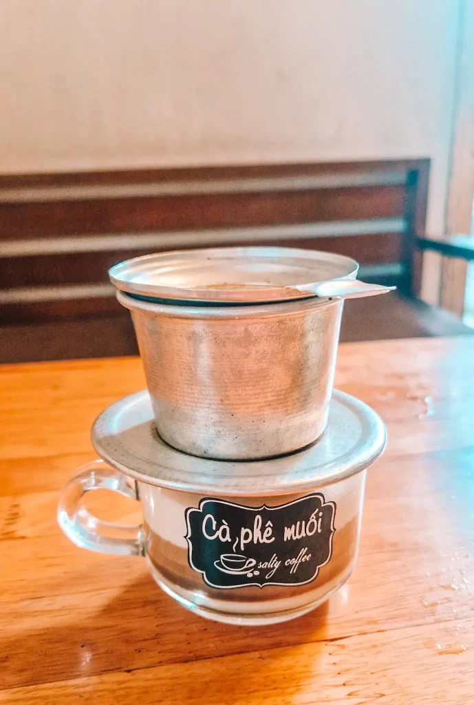 A close-up of a traditional Vietnamese phin brewing salty coffee (Cà phê muối) at Ca Phe Muoi—a must-try local drink when spending 2 days in Hue.