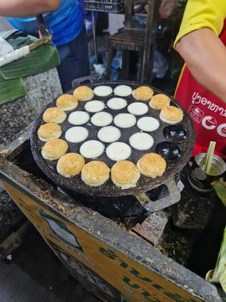 A sizzling pan of kanom krok, or Lao coconut pancakes, being cooked at a night market stall—tasting these treats is one of the best things to do in Luang Prabang.