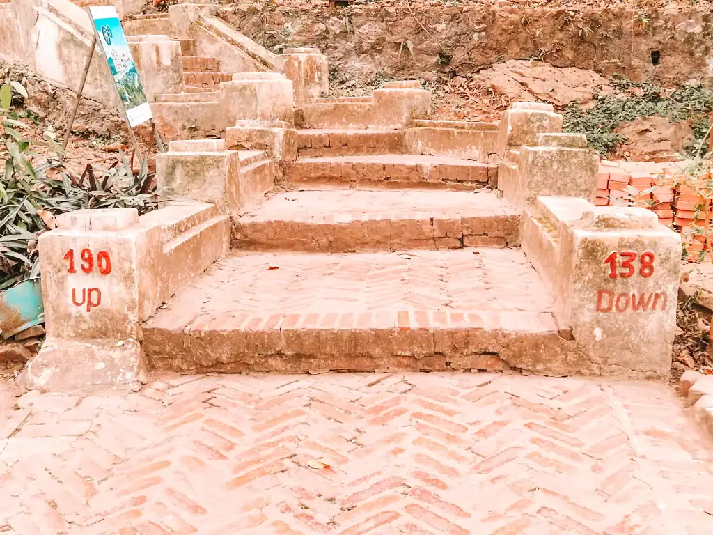 A brick staircase at Mount Phousi in Luang Prabang with red numbers marking 190 steps up and 138 steps down, offering one of the best things to do in Luang Prabang for panoramic views.