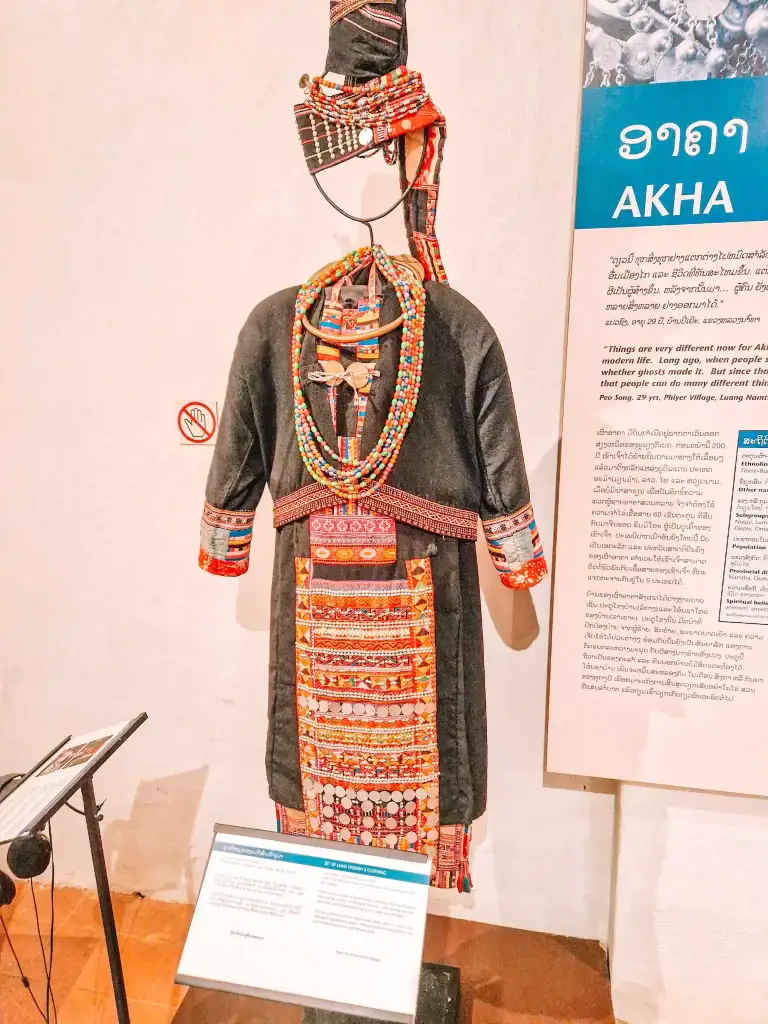 A vibrant traditional Akha outfit adorned with intricate beadwork and embroidery, displayed at a cultural museum—learning about ethnic heritage is one of the best things to do in Luang Prabang.