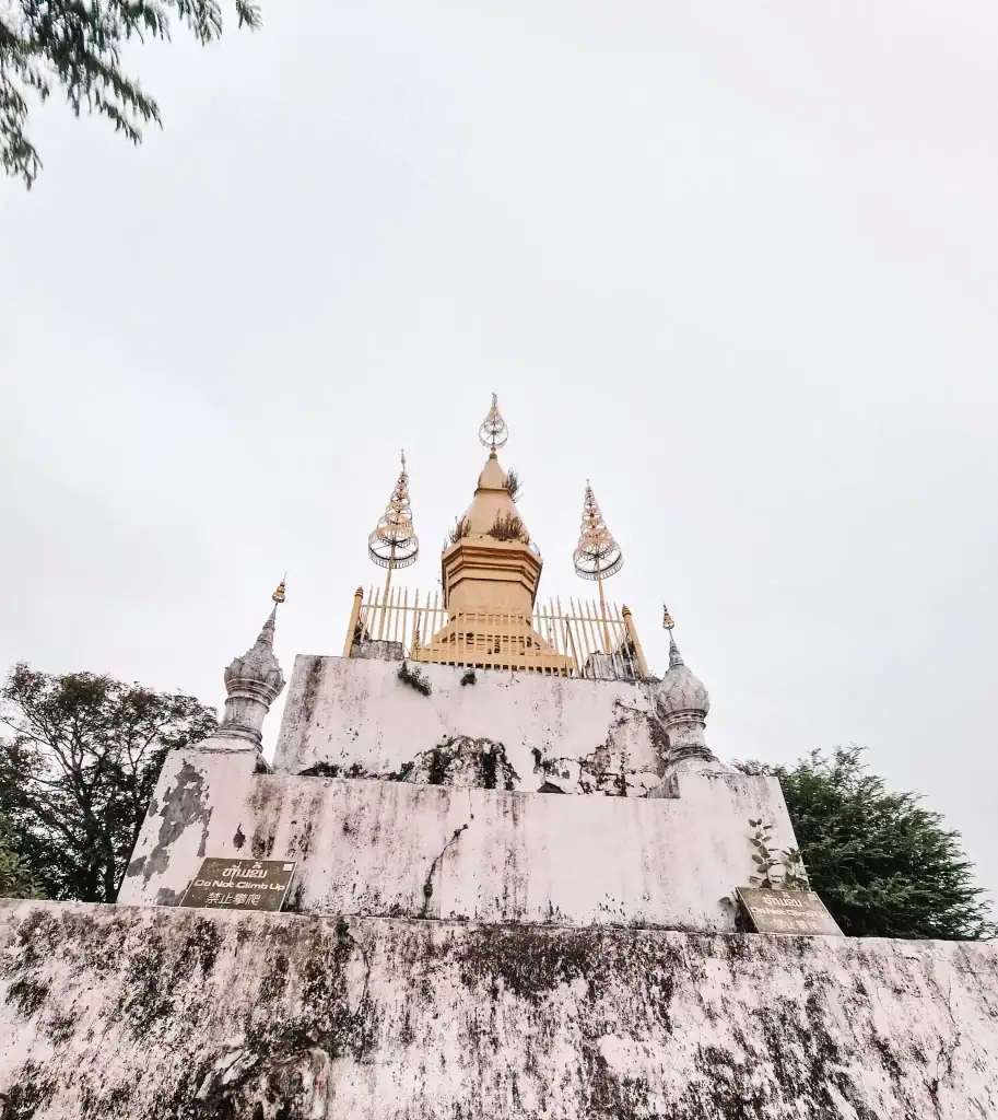 The golden That Chomsi stupa atop Mount Phousi glows against a pale sky, a spiritual and scenic climb that ranks among the best things to do in Luang Prabang.