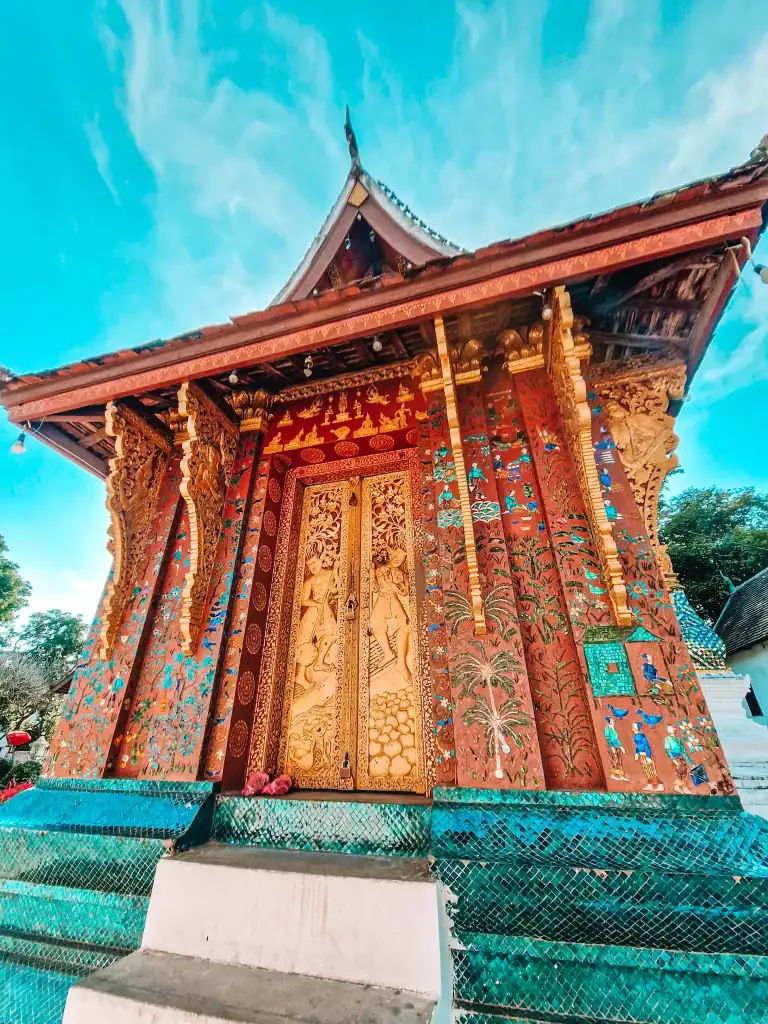 An ornately decorated temple with golden doors and vibrant mosaic artwork at Wat Xieng Thong, a stunning highlight among the best things to do in Luang Prabang.