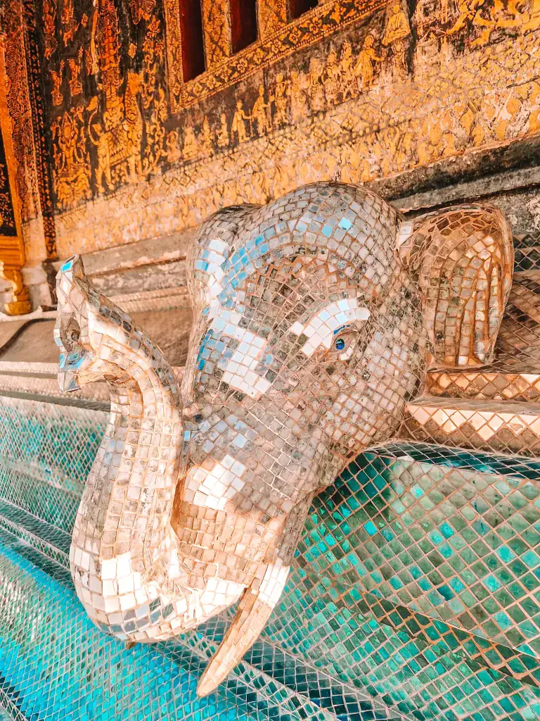 A close-up of a shimmering mosaic elephant sculpture on a temple wall, representing detailed craftsmanship that's part of the best things to do in Luang Prabang.