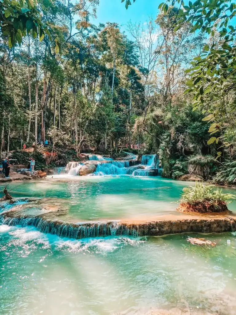 Crystal-clear turquoise pools at the base of Kuang Si Waterfalls, framed by lush jungle—swimming here is a refreshing highlight of the best things to do in Luang Prabang.