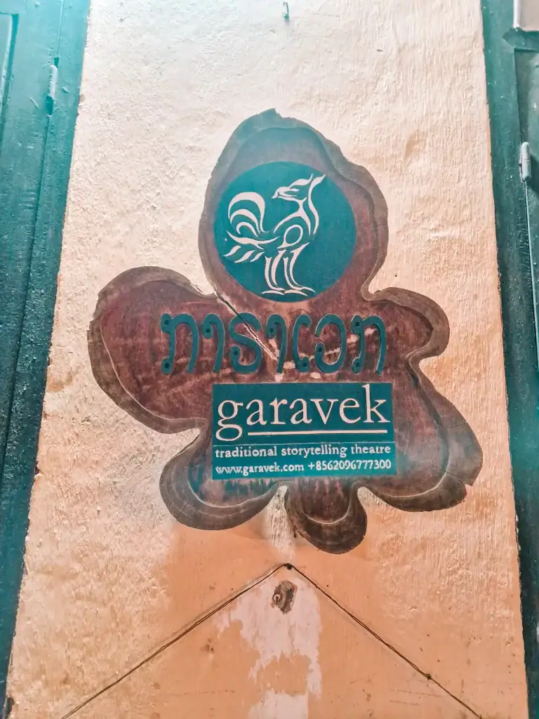 The wooden sign for Garavek Traditional Storytelling Theatre in Luang Prabang, where local legends are brought to life through live performance—an underrated gem among the best things to do in Luang Prabang.