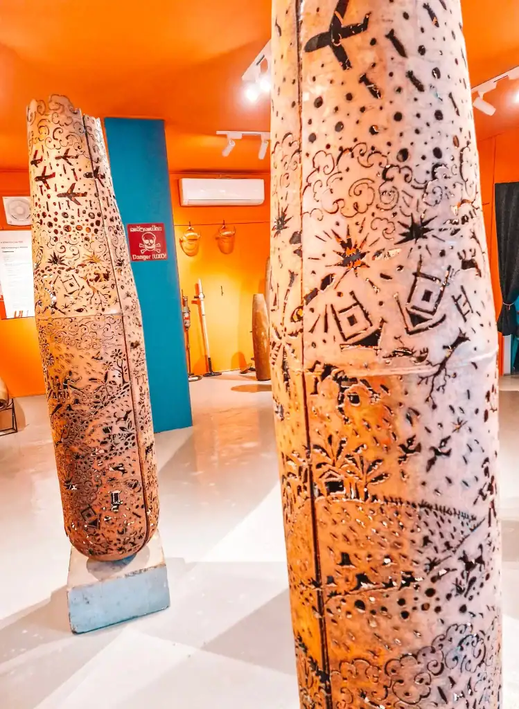 Old bomb casings intricately carved with wartime motifs, repurposed as art at the UXO museum—a powerful and educational experience that's among the best things to do in Luang Prabang.