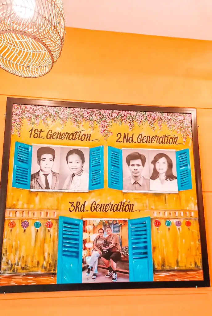 Colorful family photo wall showing three generations at one of the best vegan restaurants in Da Nang, decorated with vibrant painted shutters and floral accents.