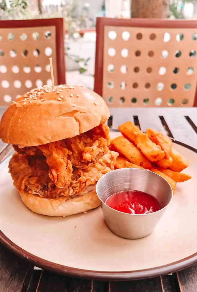 Close-up of a vegan fried mushroom sandwich with a sesame seed bun, served with thick-cut fries and ketchup at one of the best vegan restaurants in Da Nang