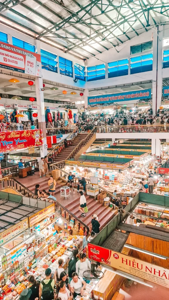 A bustling indoor market in Da Nang, filled with local vendors selling food, clothing, and souvenirs across multiple levels—perfect for visitors exploring unique things to do in Da Nang through local culture and shopping.