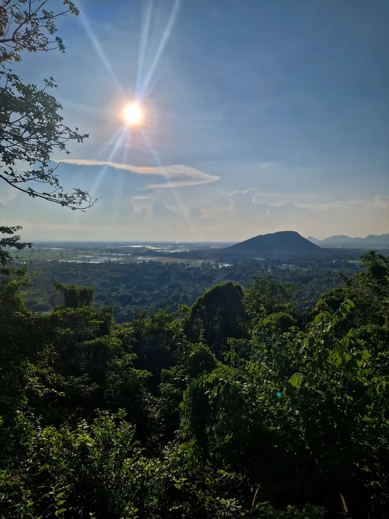 Stunning landscape view from a high vantage point in Battambang with the sun beaming above a forested valley and mountain range—an essential experience for 2 days in Battambang.