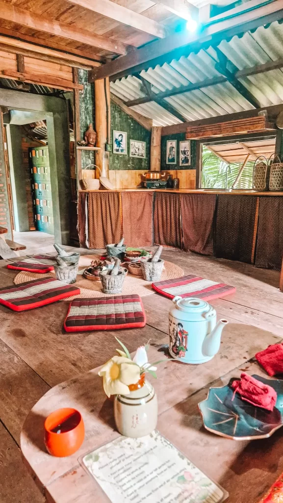 A rustic wooden room set up for a hands-on spa workshop with cushions, mortars and pestles, and herbal ingredients for body scrub making at Banteay Srey Women’s Spa in Kampot. A mindful, sensory experience to savor during 2 days in Kampot.