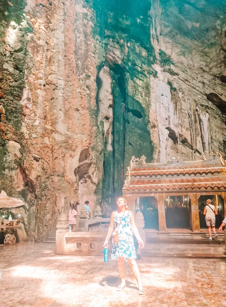 A dramatic cave temple with towering rock walls and a golden altar, bathed in natural light—one of the striking spiritual sites explored on day trips from Hoi An.