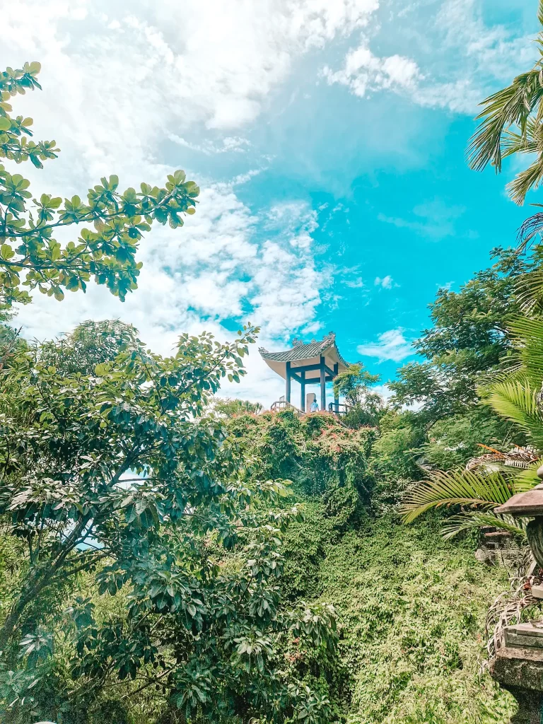 A traditional Vietnamese pavilion perched above a hill blanketed in lush greenery, offering a peaceful viewpoint on scenic day trips from Hoi An.