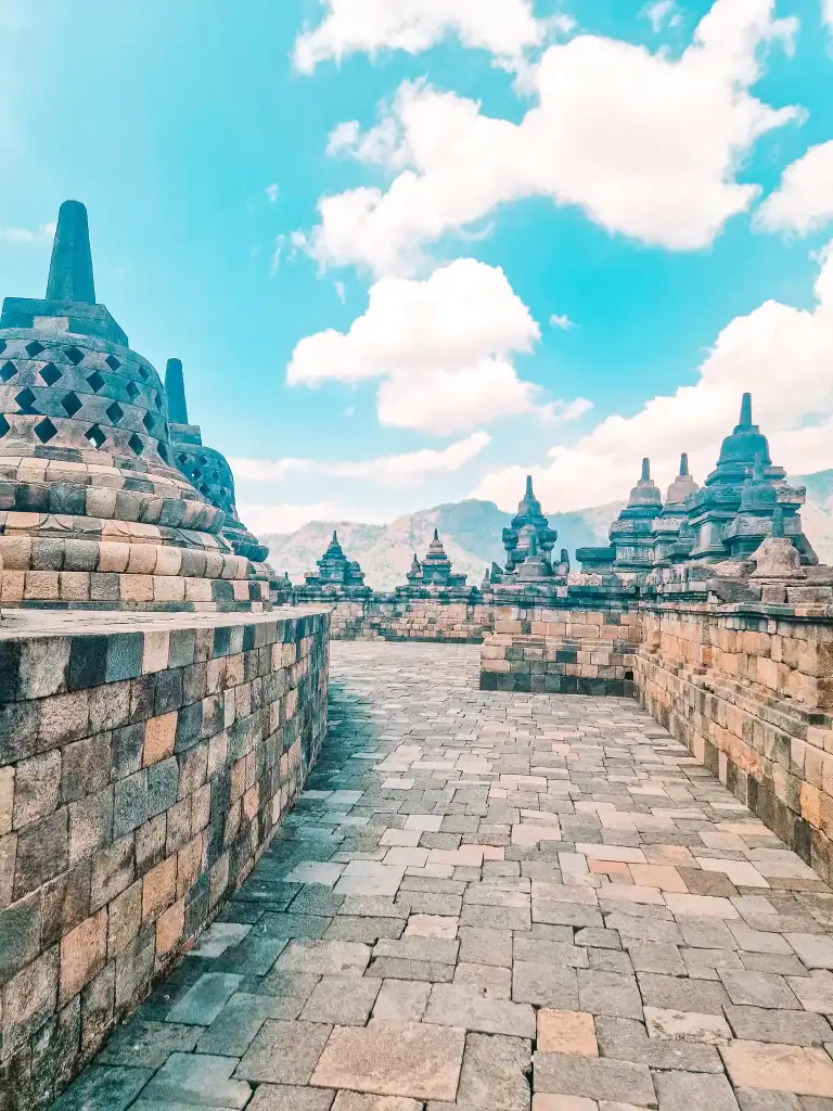 A quiet stone passage lined with bell-shaped stupas and open sky, capturing the peaceful atmosphere of walking through Borobudur’s upper terraces. Ideal for those exploring how to visit Borobudur with minimal crowds.