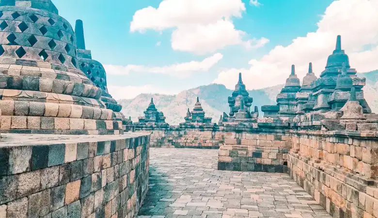 A quiet stone passage lined with bell-shaped stupas and open sky, capturing the peaceful atmosphere of walking through Borobudur’s upper terraces. Ideal for those exploring how to visit Borobudur with minimal crowds.