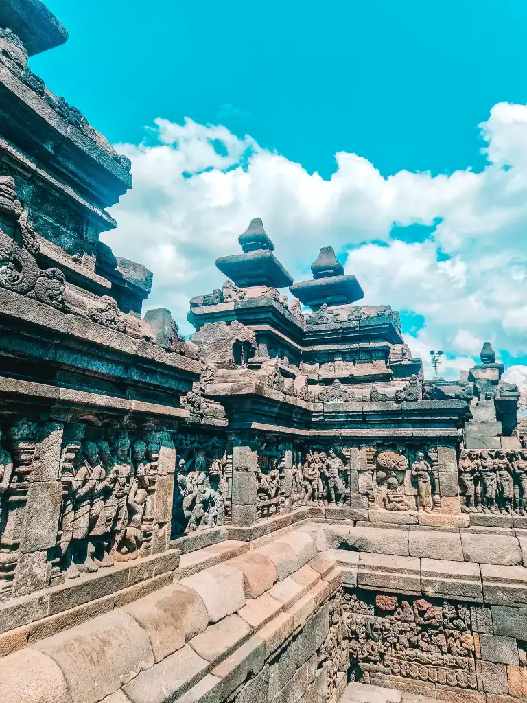 Ornate stone walls covered in rows of detailed Buddhist reliefs and figures at Borobudur. These carvings narrate sacred teachings and are a highlight for visitors appreciating the artistry.