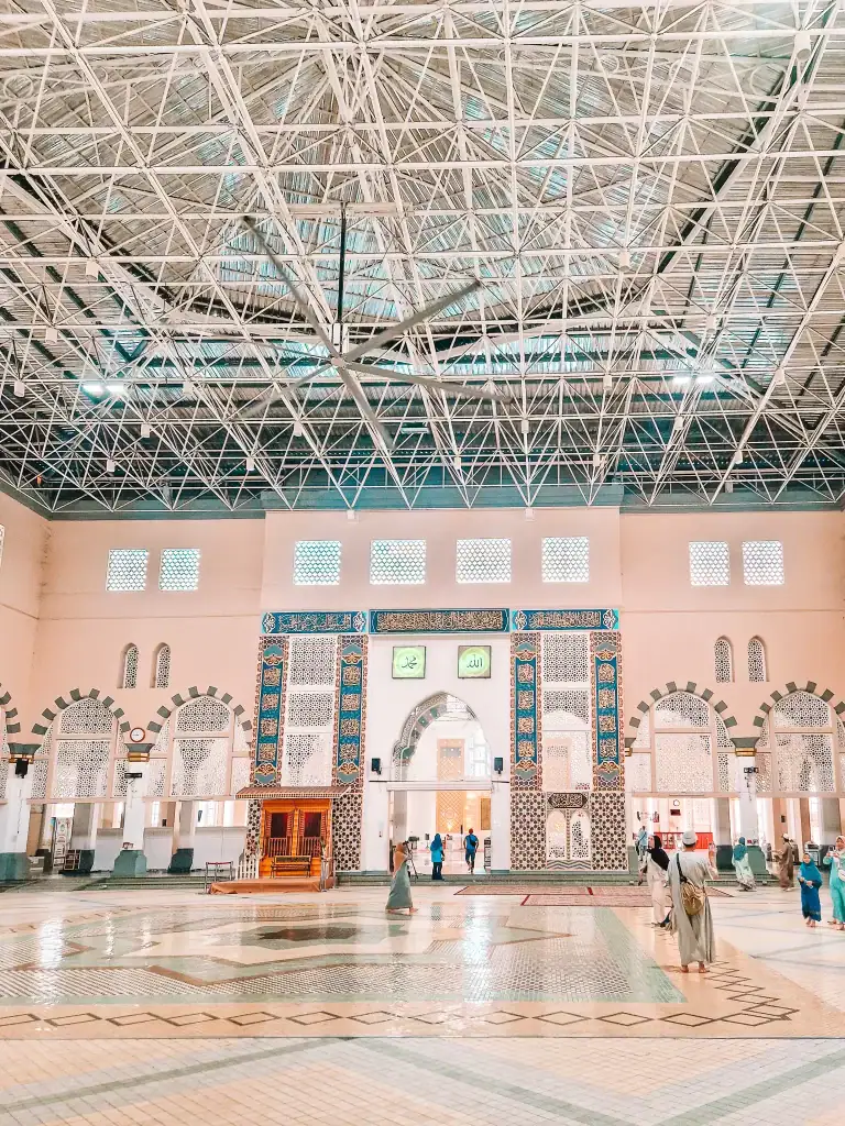 The interior of Kota Kinabalu's floating mosque features intricate Islamic architecture, detailed tile work, and a dramatic domed ceiling supported by geometric metal beams.