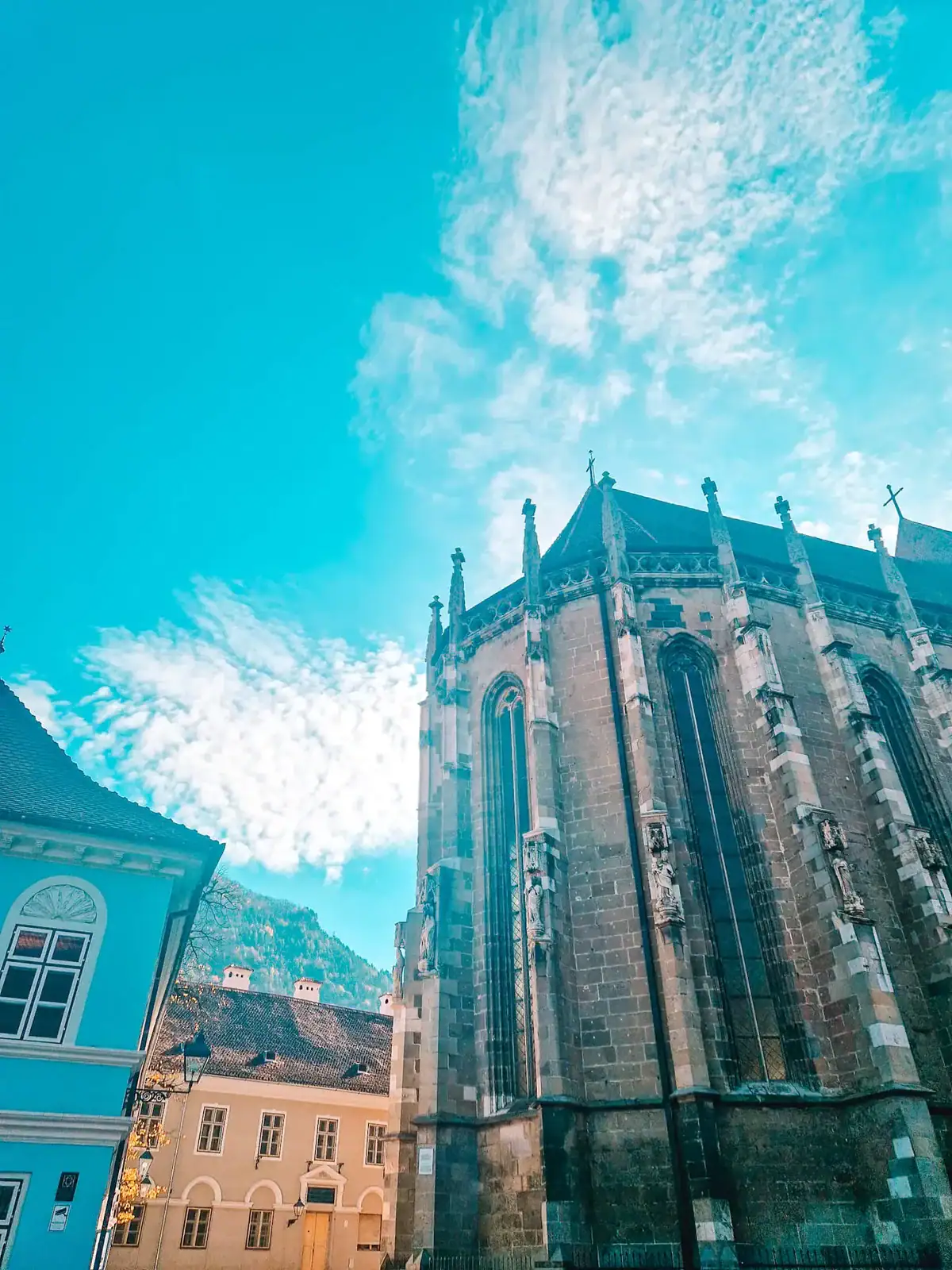 A stunning upward shot of the Black Church (Biserica Neagră) in Brasov, showing its Gothic architecture beneath a vibrant blue sky—a must-see landmark when exploring what to do in Brasov.