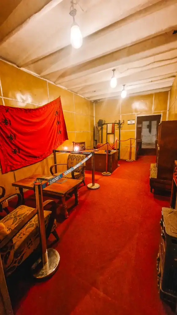 A preserved room with red carpeting, wooden furnishings, and a large red flag on the wall, once belonging to Albanian leader Enver Hoxha—part of the historical exhibits at Bunk’Art 1.