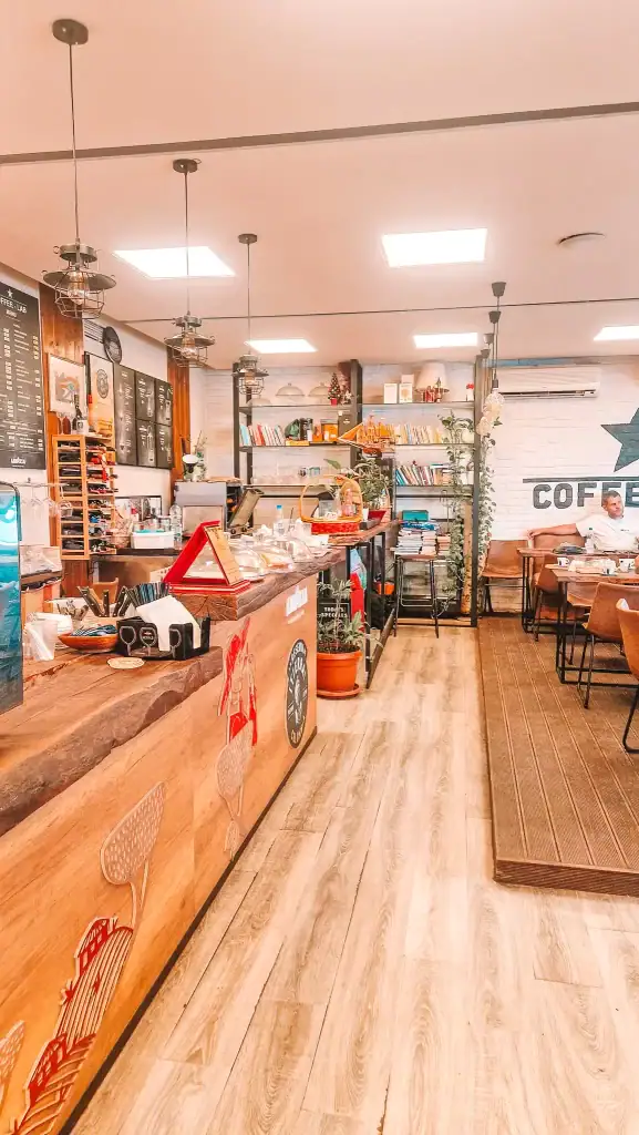 Coffee Lab in Tirana showcases a vibrant and eclectic interior with bookshelves, quirky lighting, and a wood-detailed counter. The cozy setup and diverse seating options make it a great find among cafés in Tirana for both coffee lovers and digital nomads.