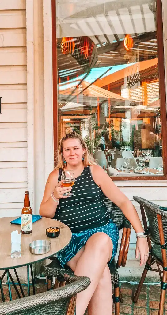 Em enjoys a cold drink and local beer at a cozy café patio with elegant glassware and warm-toned décor, soaking in the city’s charm.