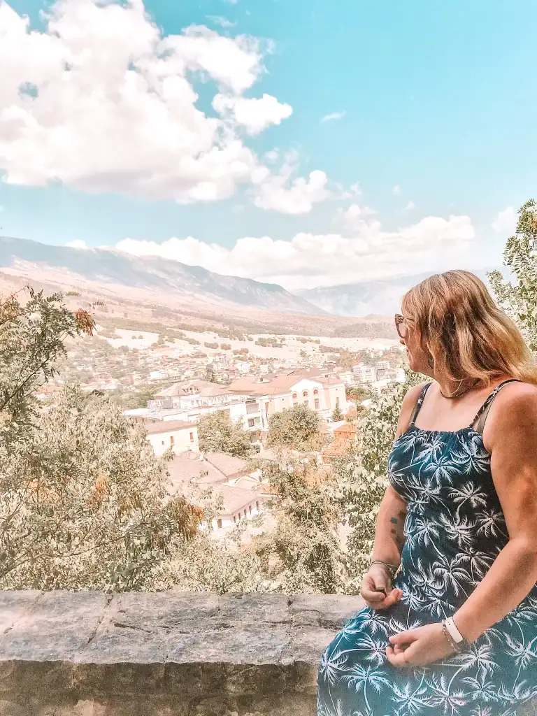 Em looks over her shoulder at the sweeping view of Gjirokaster's historic town and surrounding landscape, a serene moment that shows why Gjirokaster is worth visiting.
