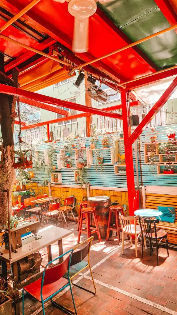 Playful and colorful patio at Radio Bar in Tirana, with painted fences, hanging planters, and mismatched furniture. A quirky, creative space that stands out among Tirana’s cafés for its artsy outdoor charm.