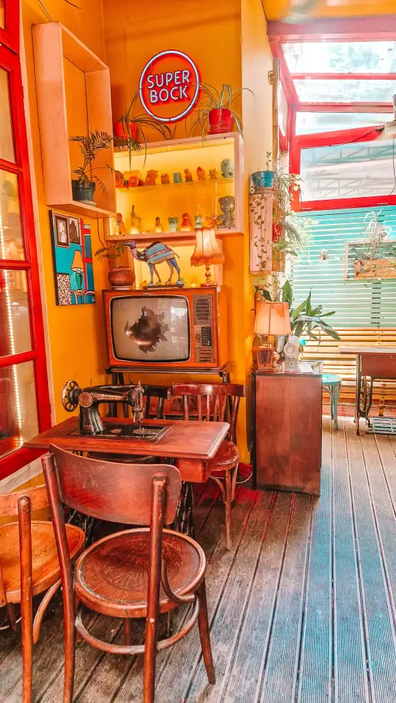 A cozy retro nook inside Radio Bar featuring a vintage TV, warm lighting, and an old sewing machine as a table. Funky décor makes this one of the most unique cafes in Tirana.