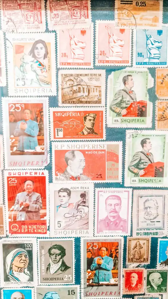 A colorful display of vintage Albanian postage stamps featuring historical figures like Mao Zedong, Stalin, and Mother Teresa, reflecting Albania’s complex political past.