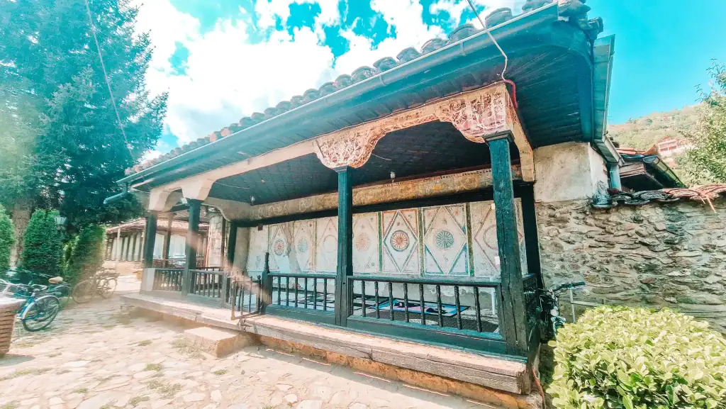 An intricately painted historic building with wooden columns and detailed geometric murals on the exterior walls.